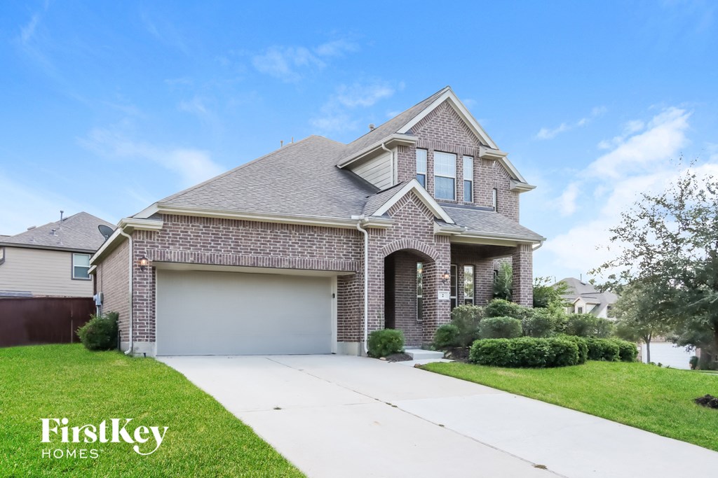 a brick house with a garage and a white driveway