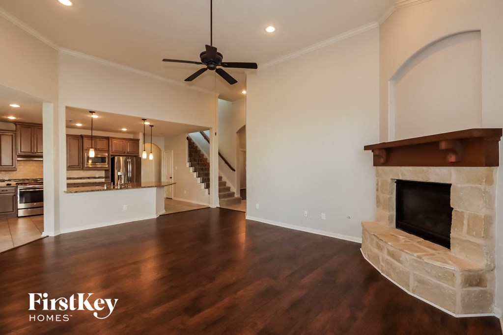 an empty living room with a fireplace and a ceiling fan