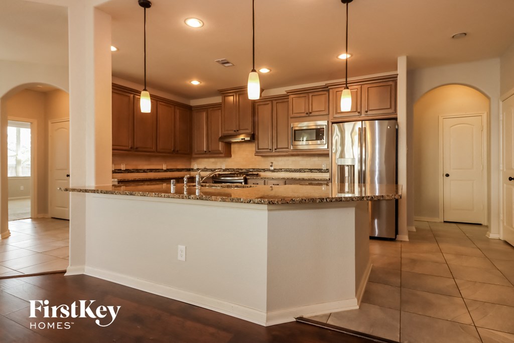 a kitchen with a large island and a stainless steel refrigerator