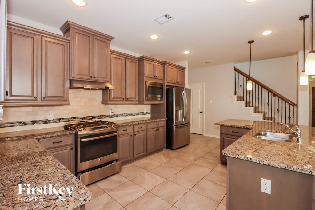 a large kitchen with granite counter tops and stainless steel appliances