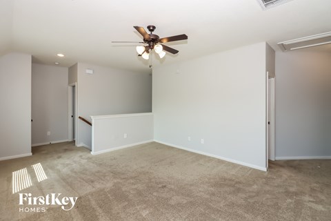 a living room with carpet and a ceiling fan