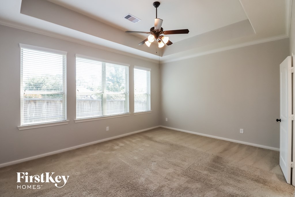 a living room with a ceiling fan and three windows