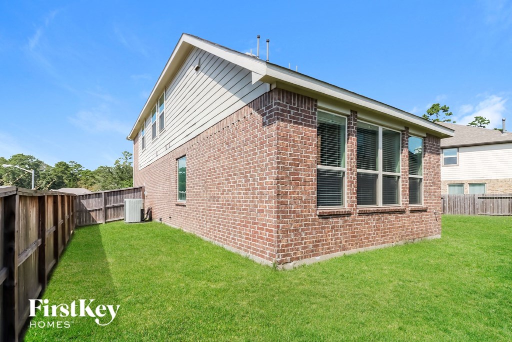 the backyard of a brick house with a yard and a wooden fence
