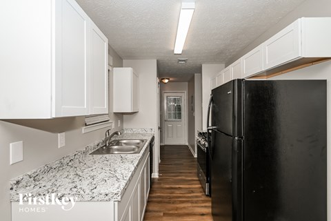 a kitchen with white cabinets and a black refrigerator