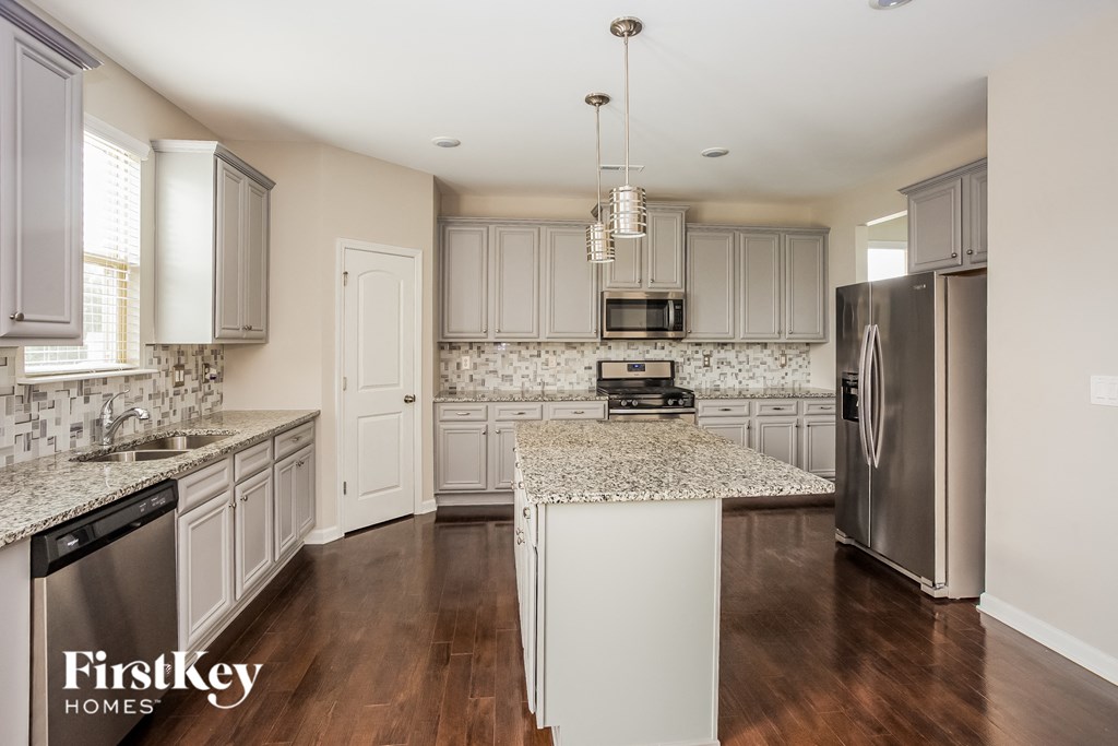 a kitchen with white cabinets and granite counter tops and stainless steel appliances