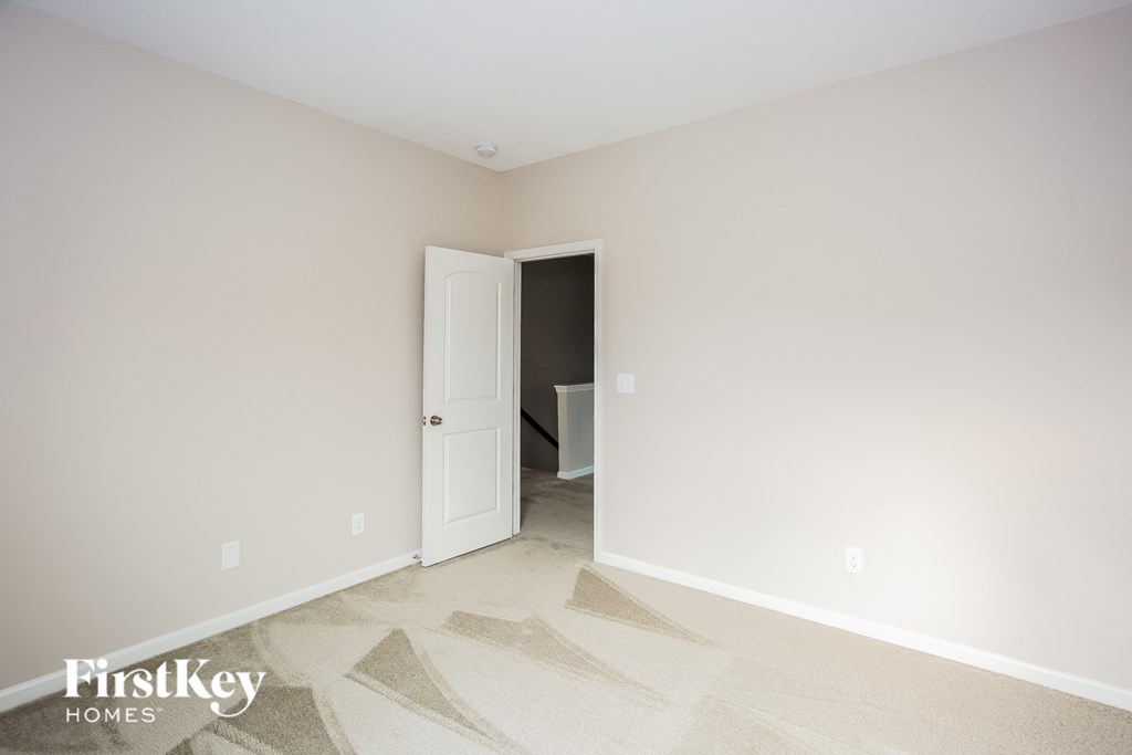 a master bedroom with a door to a bathroom and a carpeted floor