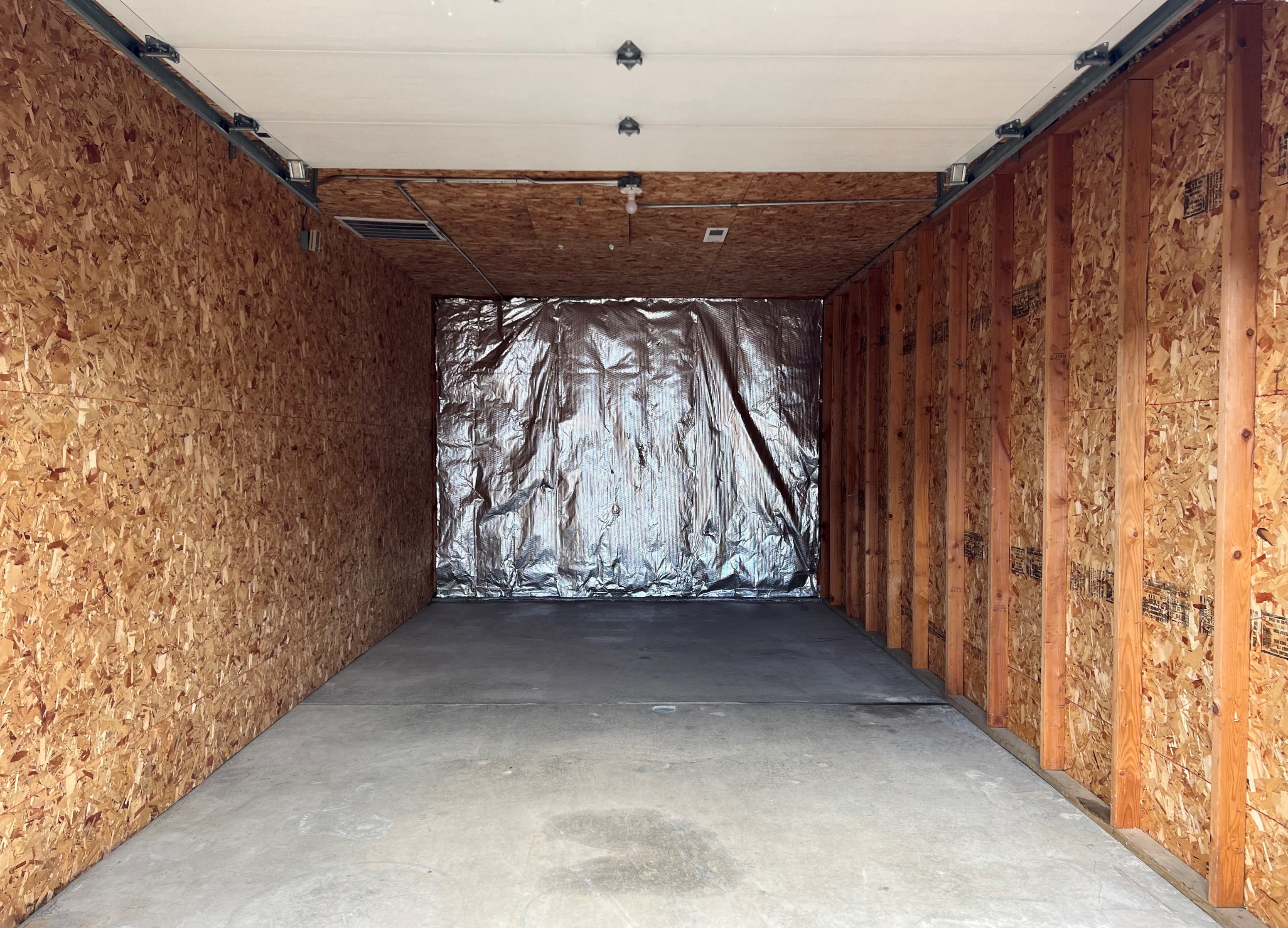 A room under construction with wooden panels on the walls and a silver tarp in the middle.