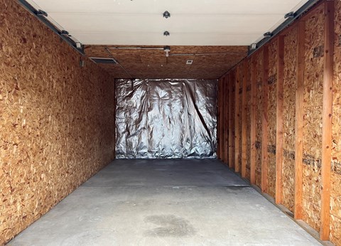 A room under construction with wooden panels on the walls and a silver tarp in the middle.