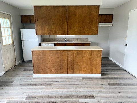 an empty kitchen with wooden cabinets and a white refrigerator