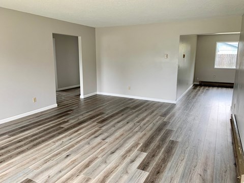 the living room and dining room of an empty home with wood flooring