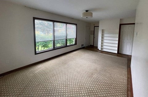 an empty living room with a large window and a carpet
