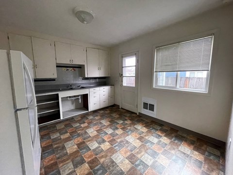 an empty kitchen with a refrigerator and a window