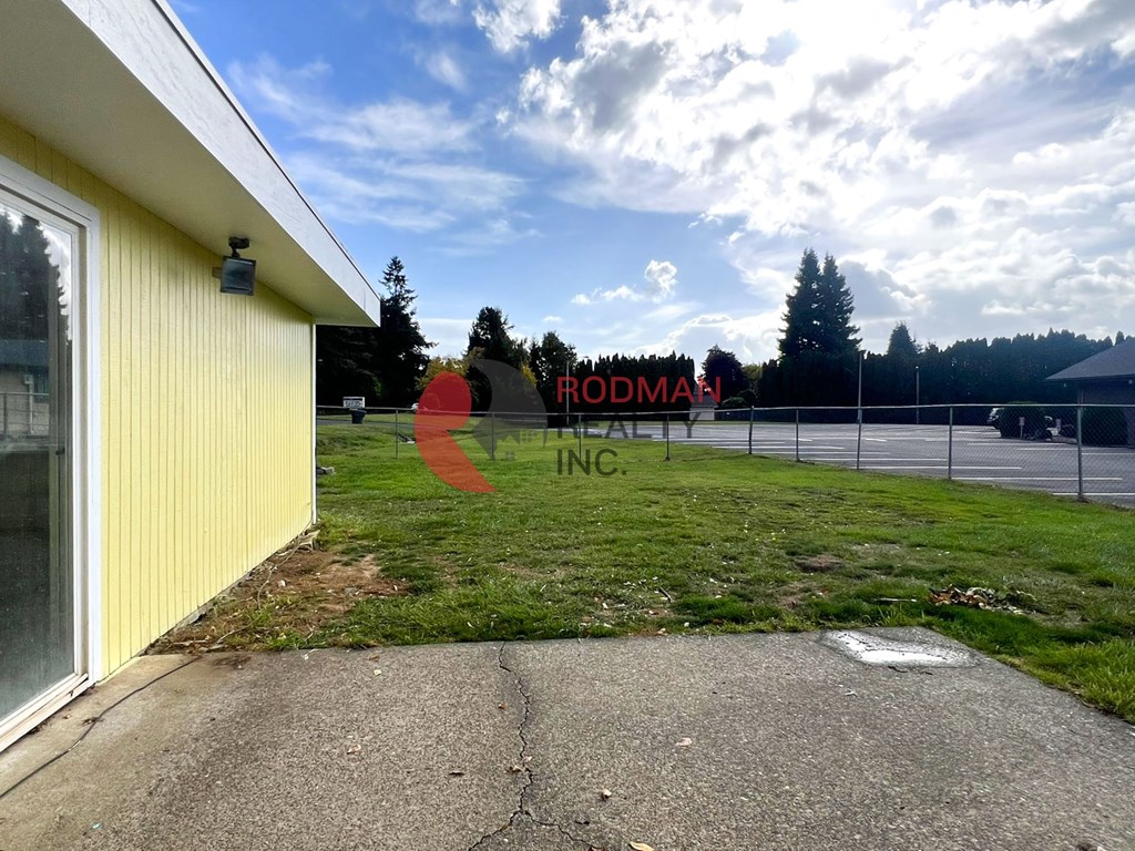 A yellow building with a sign that says "Rodman Realty" in front of a grassy area.