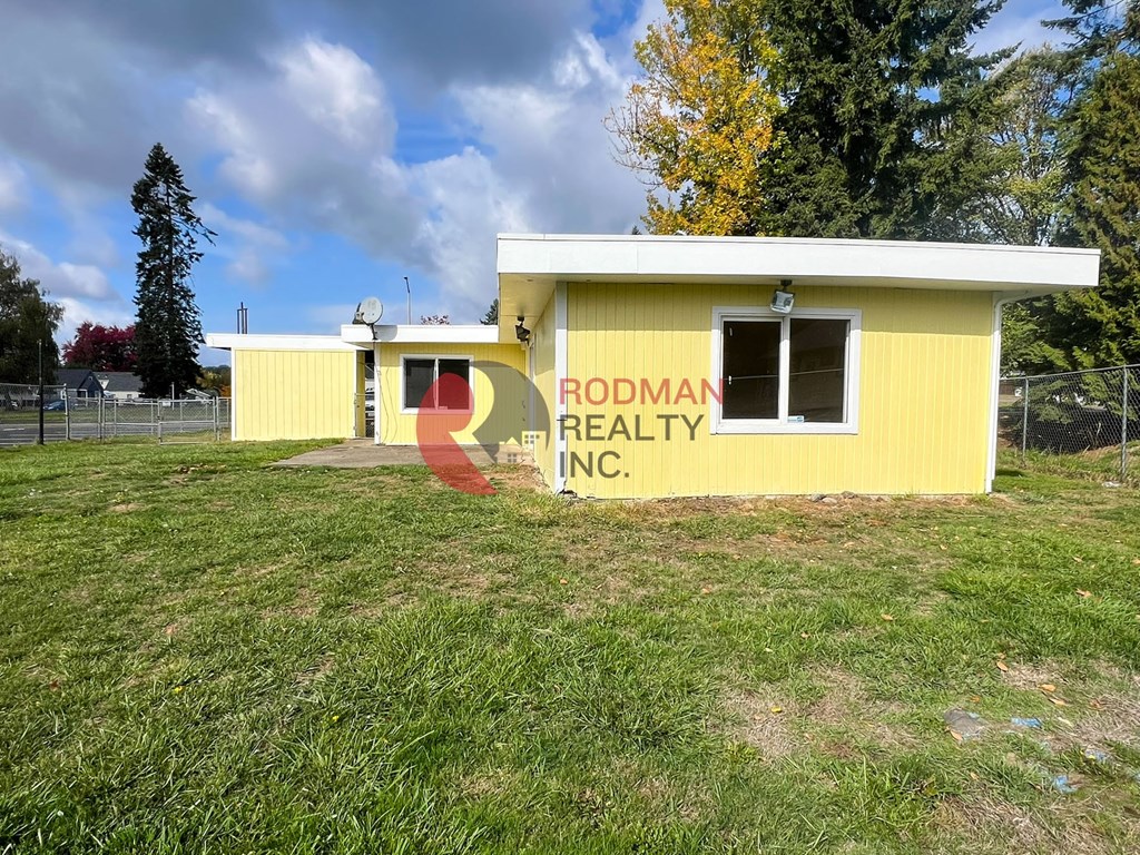 A yellow building with a sign that says Rodman Realty Inc. in front of it.