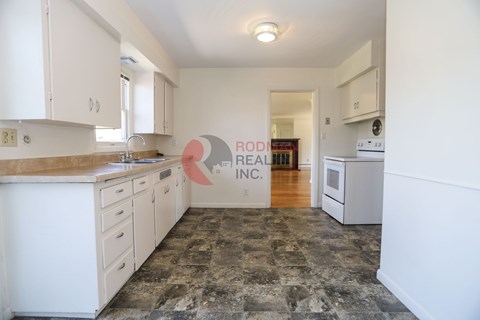 A kitchen with white cabinets and a stone floor.