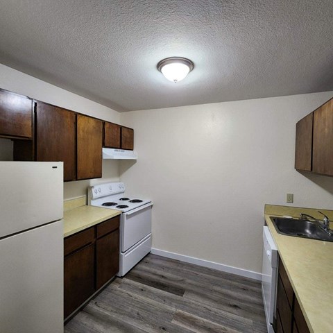 A kitchen with a white stove and wooden cabinets.