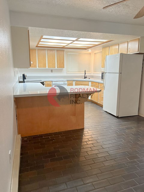 A kitchen with a white refrigerator and wooden cabinets.