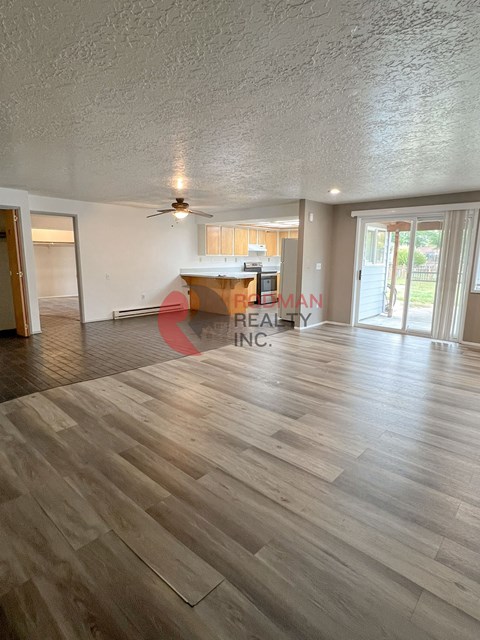 A spacious room with wooden flooring and a ceiling fan.