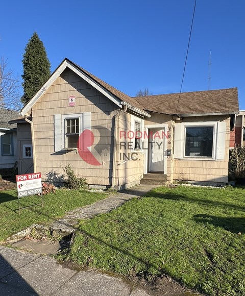 A small house with a "For Rent" sign in front.