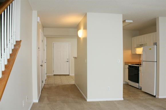 an empty kitchen with a white refrigerator and a staircase