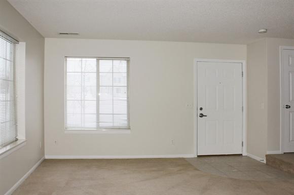 an empty living room with a white door and a window