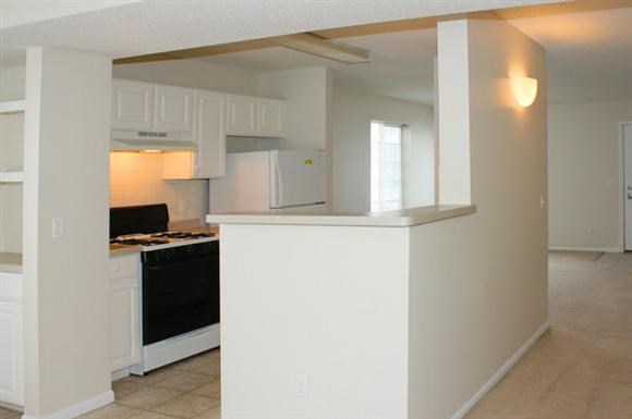 an empty kitchen with white cabinets and a black stove