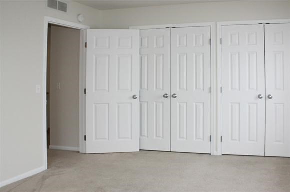 three white closet doors in an empty room