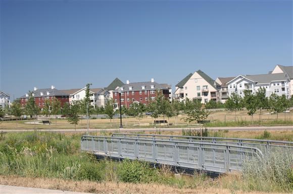 a bridge in front of a field with houses
