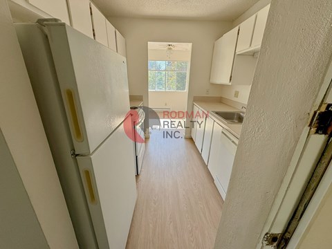 A kitchen with white cabinets and a refrigerator.