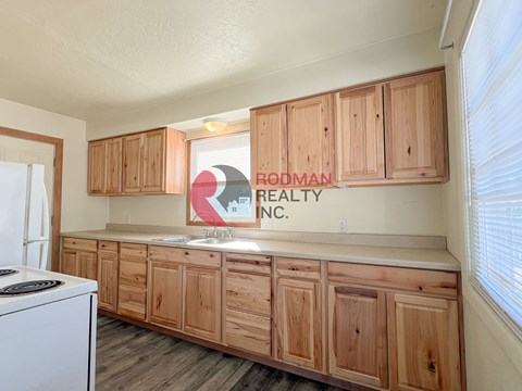 A kitchen with wooden cabinets and a sign that says "Rodman Realty Inc.".