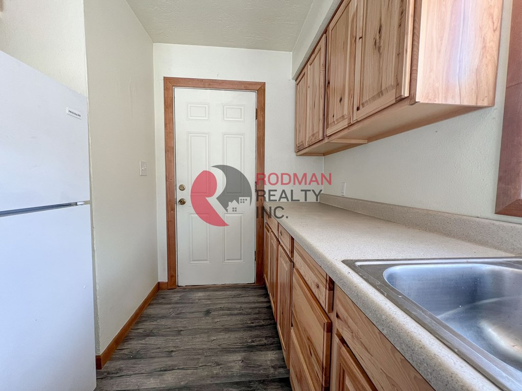A kitchen with wooden cabinets and a white fridge.