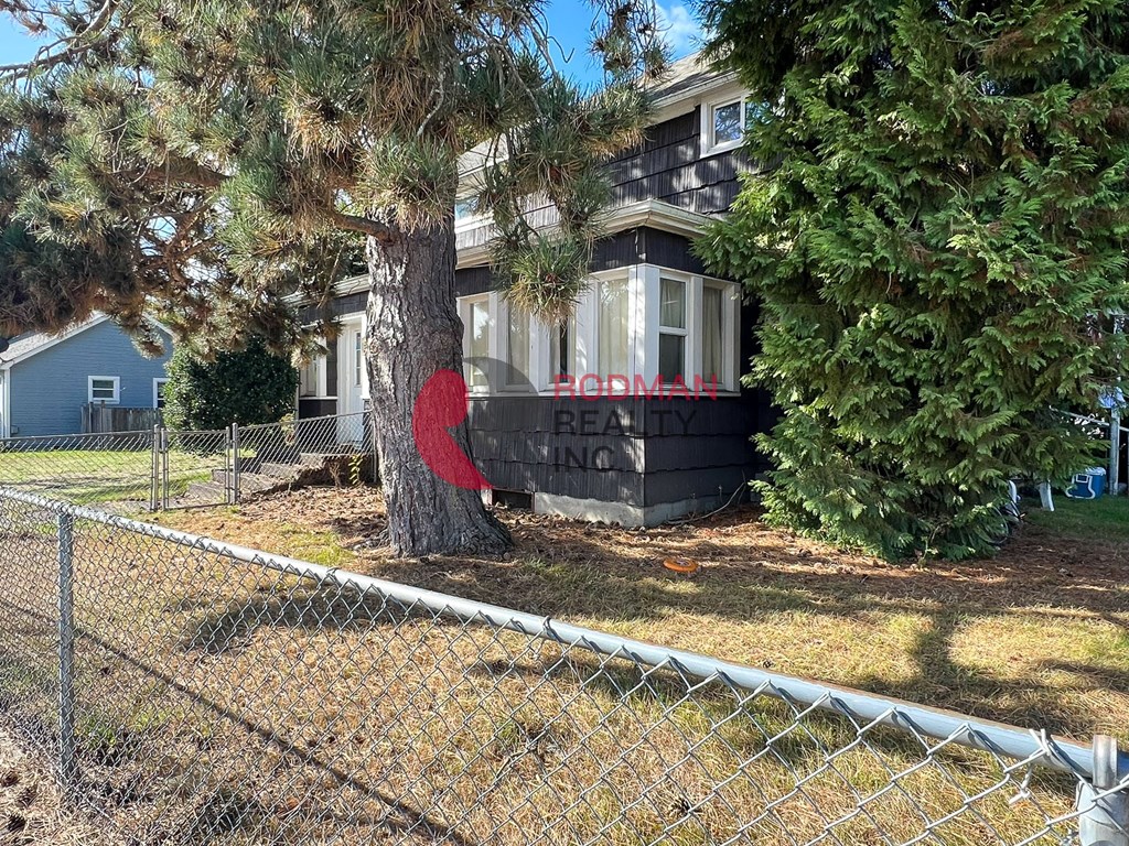 A house with a sign that says "BROKMAIL" is surrounded by trees and a chain link fence.