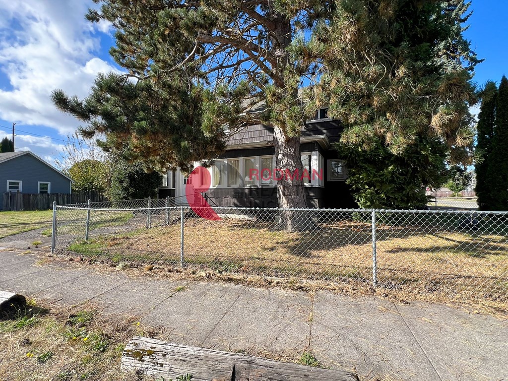 A red sign with white letters is on the side of a house.