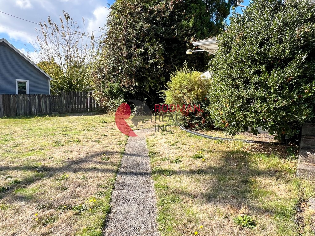 A red sign with the word "RETAIL" is in the foreground of a grassy area with a pathway leading to a house.