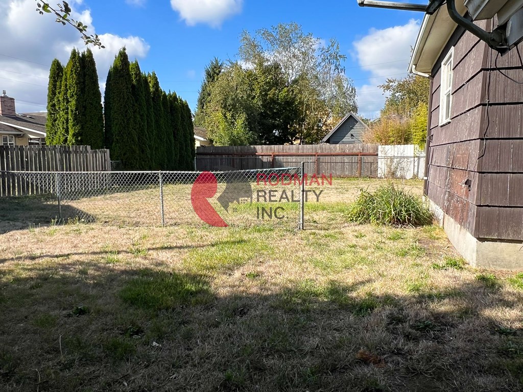 A yard with a fence and a sign that says "Real Estate Inc.".