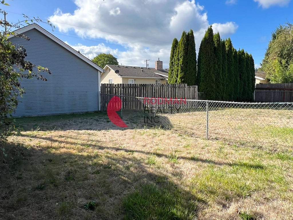 A backyard with a fence and a tree.