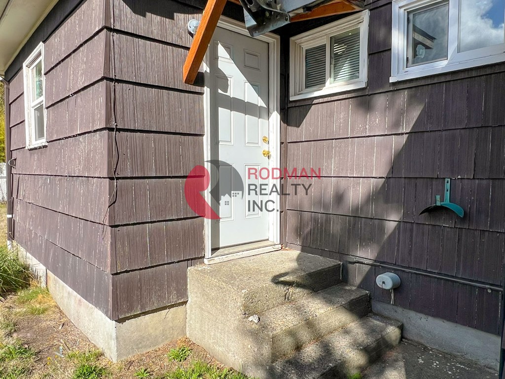 A house with a brown siding and a white door is for sale.