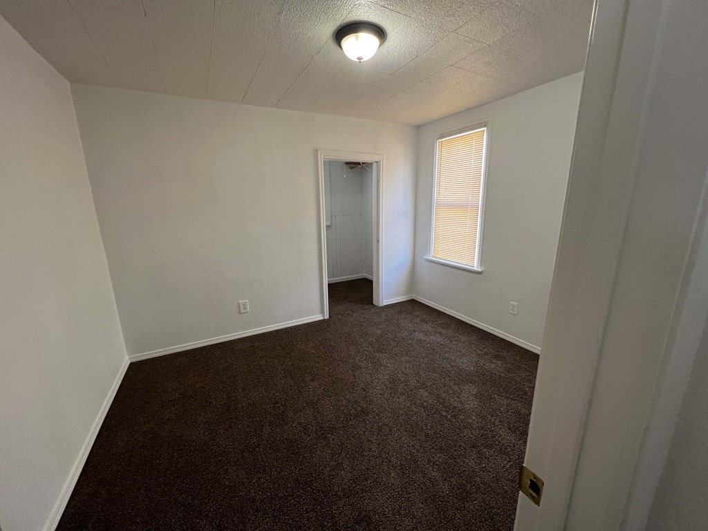 a bedroom with a carpeted floor and a door to a closet