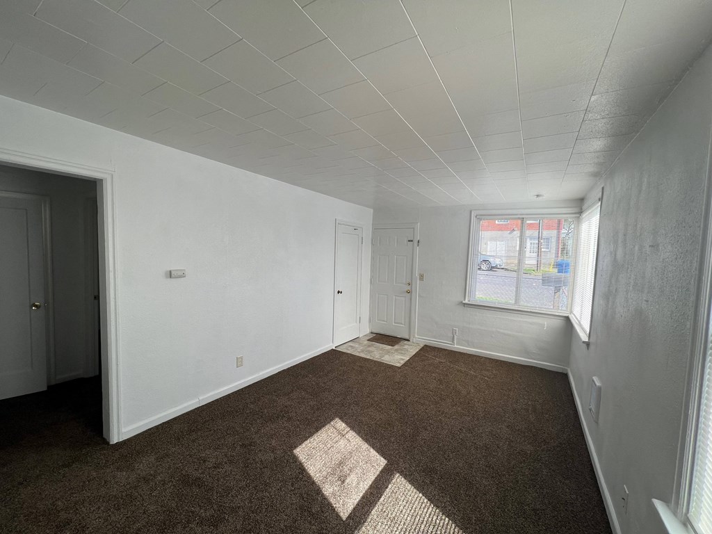 an empty room with a window and white walls