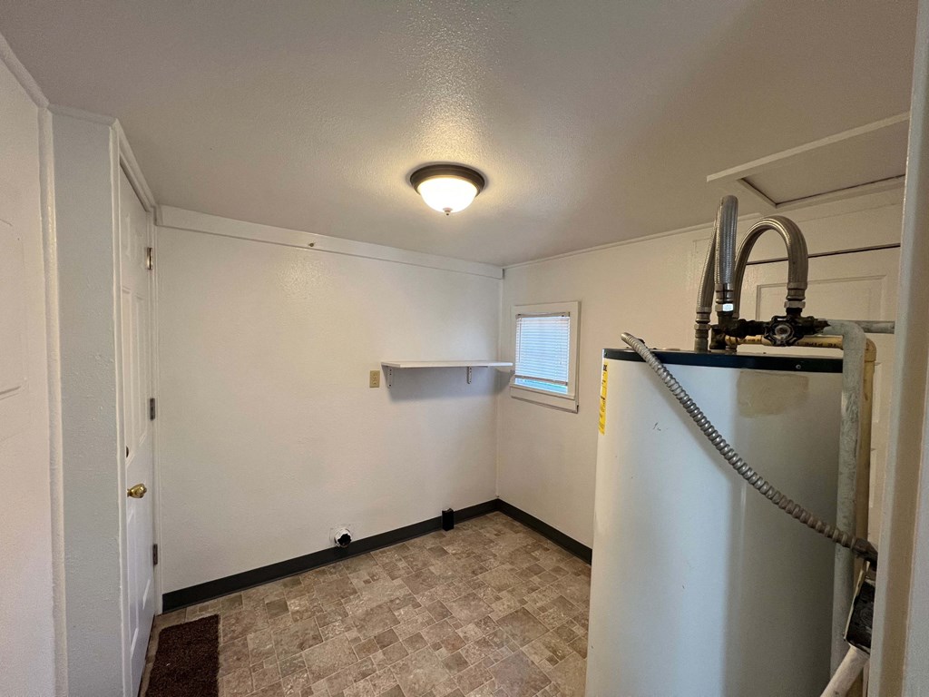 an empty room with a refrigerator and a window