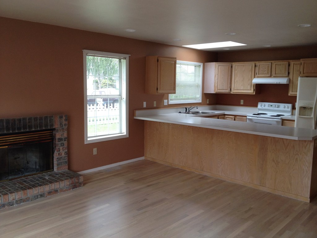 an empty kitchen with wood floors and a fireplace