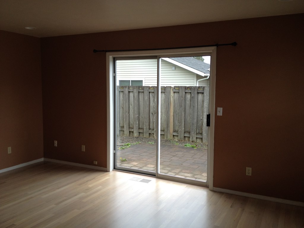 an empty living room with a sliding glass door to a patio