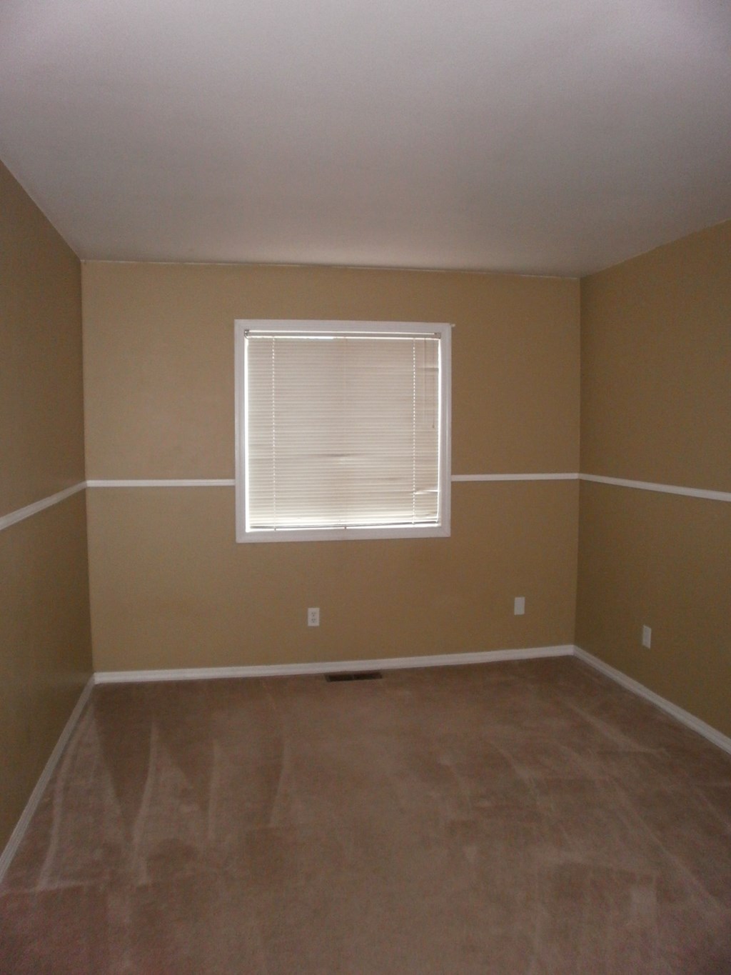 an empty room with beige walls and a window
