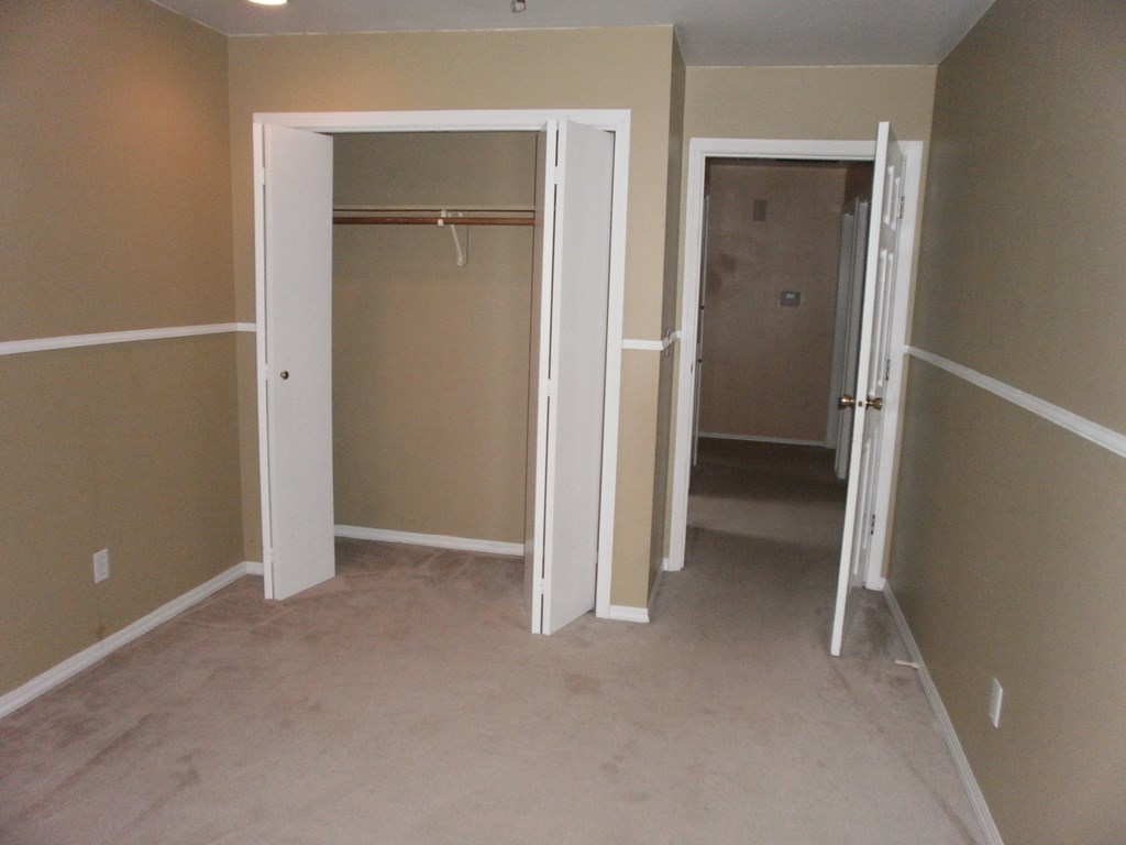 an empty room with a closet and a hallway with two doors