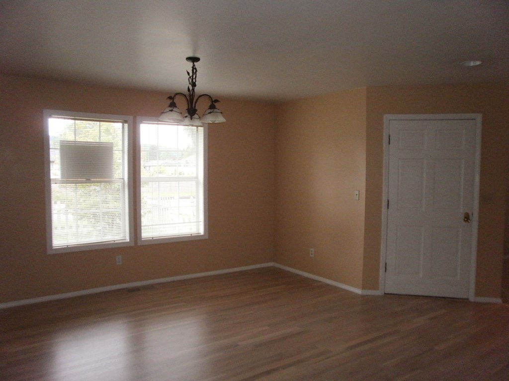 an empty living room with a white door and a window