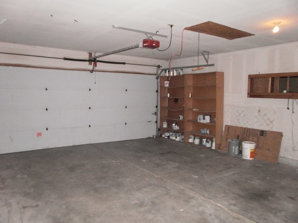 a garage with a white wall and shelves in it