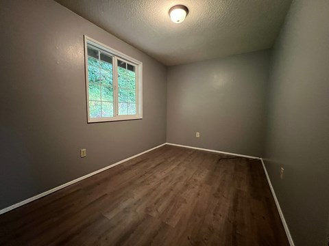 A room with a window and wooden flooring.