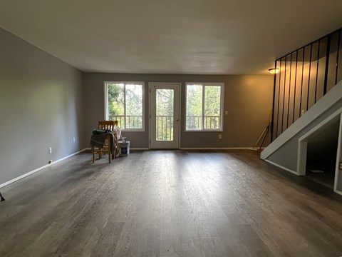 A room with wooden floors and a dining table with chairs.