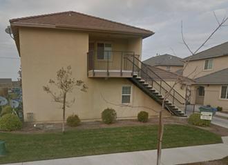 a beige house with a balcony and a sidewalk