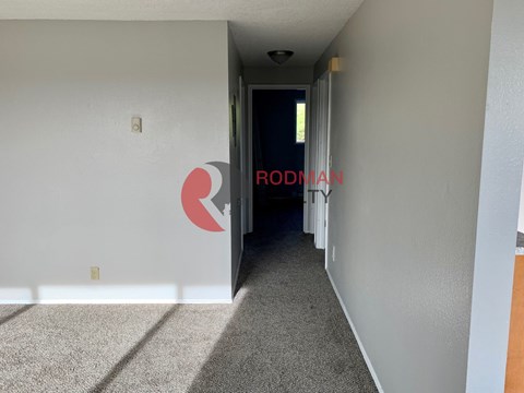 A hallway with a carpeted floor and a door at the end.